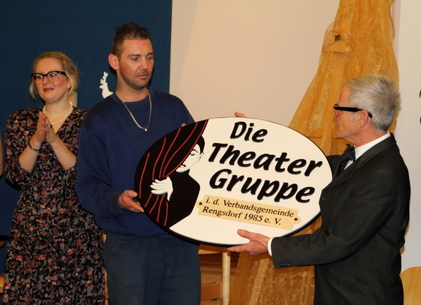 Ein Gefangener aus der Arbeitstherapie Holz überreicht das von ihnen angefertigt Schild mit dem Emblem der Theatergruppe aus der Verbandsgemeinde Rengsdorf.
