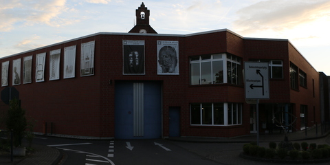 An der Außenmauer und der Außenpforte sind weithin sichtbar für die Öffentlichkeit einige der Banner der Ausstellung 