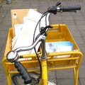 Postfahrrad mit einer gelben Postkiste und der Inhalt sind Briefe.