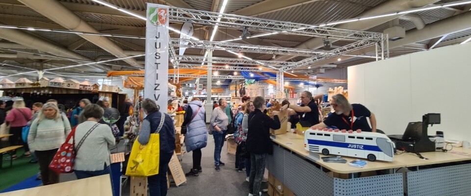 Zu sehen sind Besucher und Standbetreuer aus der Justiz am Messestand des "Knastladen".