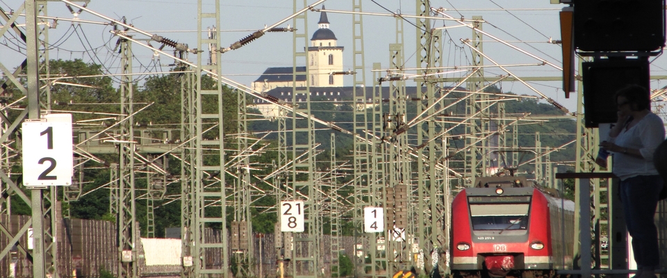 Einfahrt eines Zuges in den Bahnhof Troisdorf. Im Hintergrund ist die Abtei von Siegburg zu sehen.