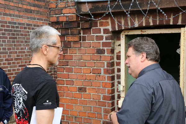 Christopher Gries (Mitarbeiter des EL-DE-Hauses) im Gespräch mit dem Anstaltsleiter vor dem Eingang zum ehemaligen Leichenkeller.