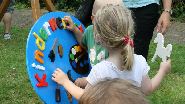 Eine magische Anziehungskraft hatten die bunten Buchstaben und Symbole auf Kinder. Die Kinder versuchten immer wieder Buchstaben oder Symbole von dem Schild der Kinderwerkstatt zu lösen.