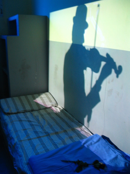 Videoinstallation zeigt den Geigenspieler als Schatten in seinem Haftraum beim spiel auf der Geige.