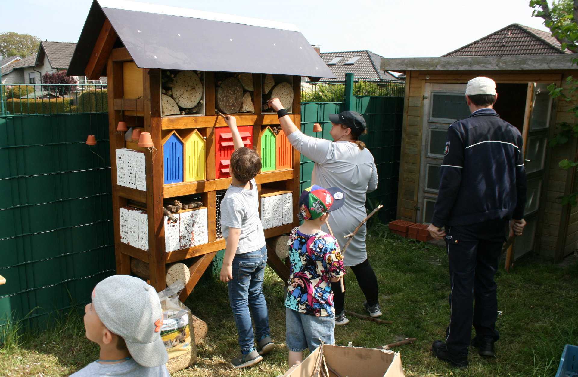 Die Kinder befüllen das Grundgerüst des Insektenhotels zusammen mit den Betreuern mit den vorbereiteten Materialien.